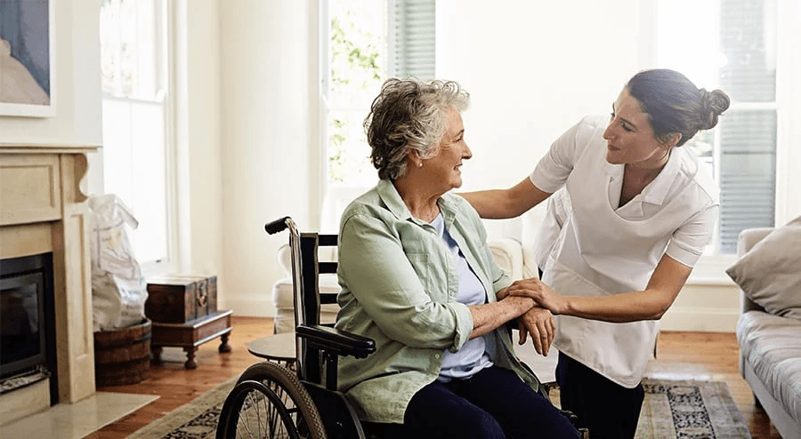 Caregiver offering calm companionship to an older woman in a wheelchair.